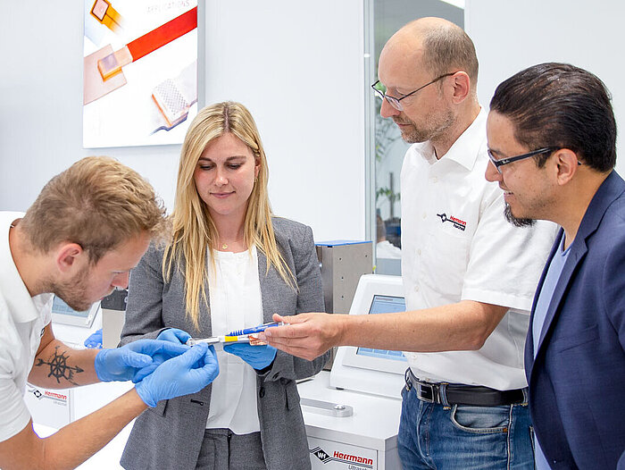 Mehrere Herrmann Ultraschall Mitarbeiter betrachten das Ergebnis einer Metallschweißung