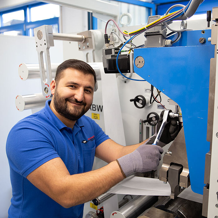L'employé d'Herrmann Ultraschall règle une machine à souder avec une clé à cliquet